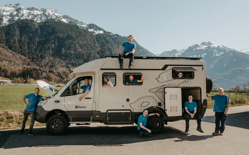Das Team von Camptech Lüthi vor den Alpen mit einem umgebauten Camper